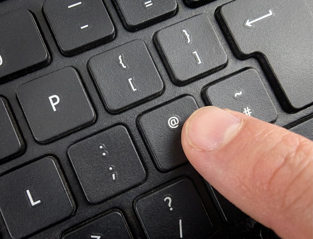 Keyboard with finger about to press the @ key